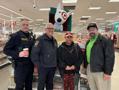 Four adults, two in police uniforms, pose in a store.