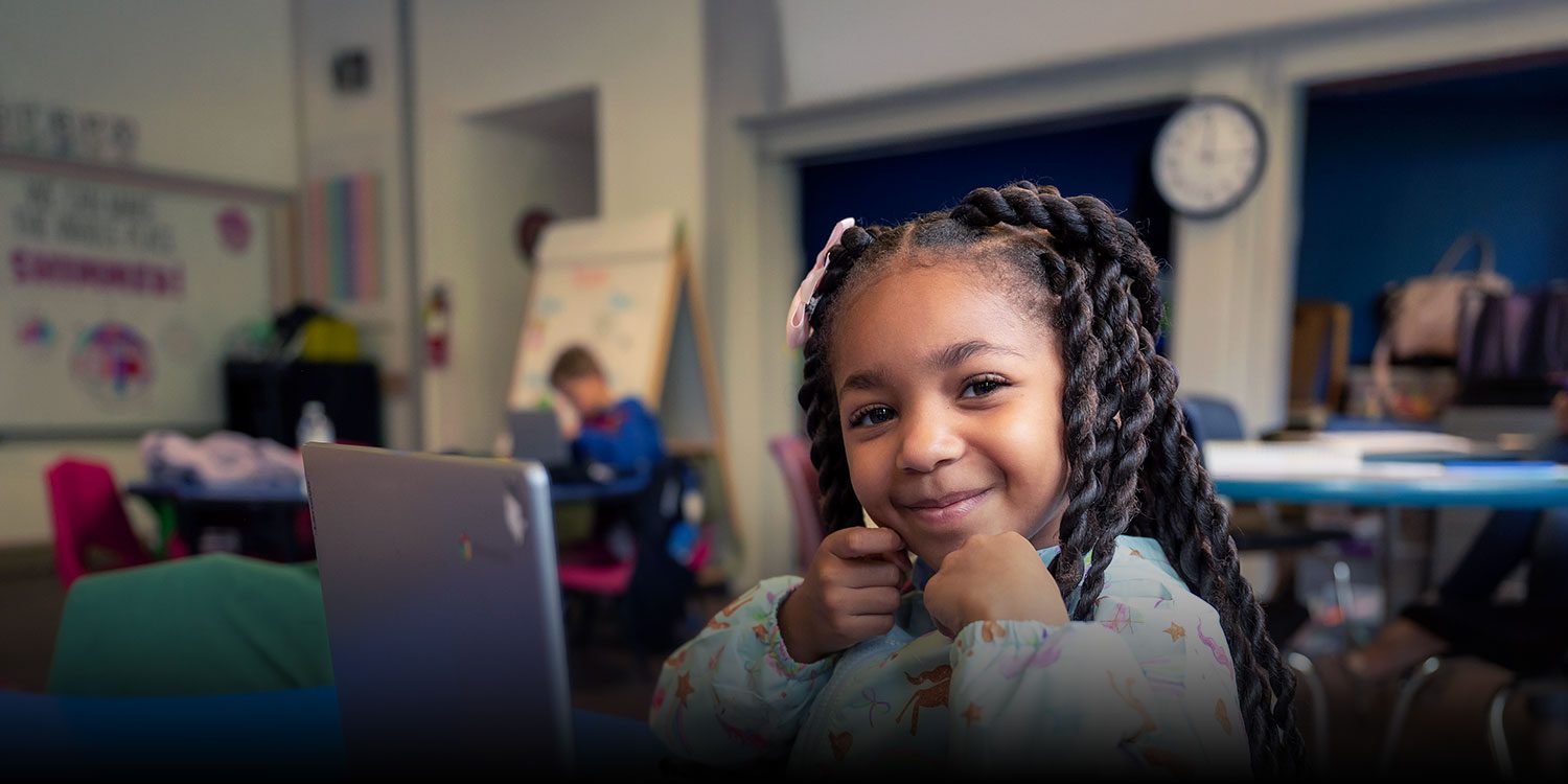 Smiling student in a classroom with a laptop